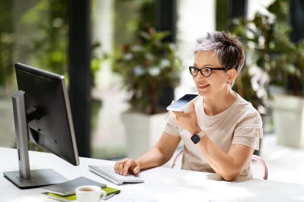 A person sitting at a desk in a well-lit room, looking at a laptop screen with a bank's website open. The person is holding a debit card and smiling.